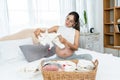 Asian single mother with big belly is about to give birth preparing clothes for her new baby. woman sits on the bed folding Royalty Free Stock Photo