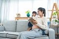Asian single mother Pregnant woman sitting on sofa in living room reading with her lovely daughter sitting on her lap, mother Royalty Free Stock Photo