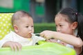 Asian sister feeding food for her little brother with love on the plastic chair Royalty Free Stock Photo