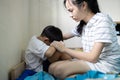 Asian sister touching shoulder,holding hand,comforting and caring for her little brother,depressed kid boy sitting and crying on