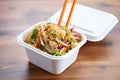 asian slaw in takeout container, chopsticks on top