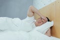 An Asian sleeping in bed has a severe headache, a man sick at home with a duvet cover Royalty Free Stock Photo