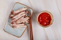 Asian sliced fried meat on a plate with sauce and chopstick