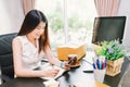 Asian small business owner work at home office, using mobile phone call, writing confirm purchase order on notebook Royalty Free Stock Photo