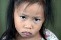 Asian small girl pucker up her mouth feel upset or dissatisfied head shot studio portrait on beige background, concept of naughty