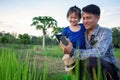 Asian smart farmer father with his happy little girl daughter using digital tablet outdoors in family organic farm Royalty Free Stock Photo