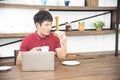 Asian smiling young man with casual  red t-shirt enjoy having breakfast, Young man cooking food and drink in the Royalty Free Stock Photo