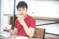 Asian smiling young man with casual red t-shirt enjoy having breakfast, eating sandwich, Young man cooking in the kitchen Royalty Free Stock Photo