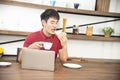 Asian smiling young man with casual  red t-shirt enjoy having breakfast in the kitchen Royalty Free Stock Photo