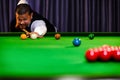 Asian snooker player while aiming to white ball shoot to hit the red ball group set in game on table Royalty Free Stock Photo