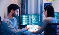 Asian software developers teams working on multiple screens displaying code and application diagrams at night in modern office