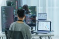 Asian software developers working on multiple screens displaying code and application diagrams in a modern office