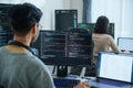 Asian software developers working on multiple screens displaying code and application diagrams in a modern office