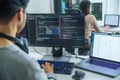 Asian software developers working on multiple screens displaying code and application diagrams in a modern office