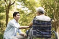 Asian son comforting wheelchair bound father