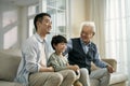 Asian son father grandfather watching soccer game on TV together at home Royalty Free Stock Photo