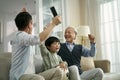 Asian son father grandfather watching soccer game on TV together at home Royalty Free Stock Photo