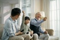 Asian son father grandfather watching soccer game on TV together at home Royalty Free Stock Photo