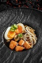 Asian soup with noodles ramen, with miso paste, soy sauce, greens,mushrooms and baked salmon. On a black stone background. Macro Royalty Free Stock Photo