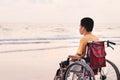Asian special child on wheelchair on the sea beach with sunset on travel Royalty Free Stock Photo