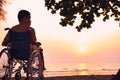 Asian special child on wheelchair on the sea beach with sunset on travel Royalty Free Stock Photo