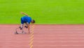 Asian speed runner on stadium track, alert and ready, anticipation building, geared to start his run