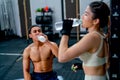 Asian sport man and woman drink water from bottle after finish of training in fitness gymm