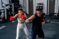 Asian sport trainer man help woman to practice with boxing for good action and movement in fitness gym