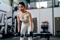 Asian sport woman stand and stay in position of exercise with hold dumbbells to lift up and down also look forward in fitness gym