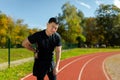 Asian sportsman has severe pain in back and abdominal muscles, man peed training in stadium on sunny day massaging side