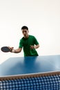 Asian sportsman playing table tennis, eyeing ball for precise hit and make goal in motion against white background.