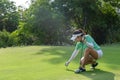 Asian sporty woman putt golf ball on tee off with club in golf course on evening on time for healthy sport. Royalty Free Stock Photo