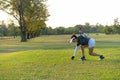 Asian sporty woman putt golf ball on tee off with club in golf course on evening on time for healthy sport sunset background. Royalty Free Stock Photo