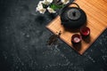 Asian spring tea ceremony. Metal black teapot, ceramic cups, bamboo mat and cherry blossom branch artificial. Black stone grunge