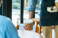 Asian staff wearing apron serving hot black coffee cup to customer on table in cafe coffee shop