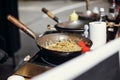 Asian street food festival in city. Chef cooking noodles and vegetables in a pan on fire. Fried chinese japanese noodles with Royalty Free Stock Photo