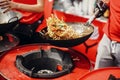 Asian street food festival in city. Chef cooking noodles and vegetables in a pan on fire. Fried chinese japanese noodles with Royalty Free Stock Photo