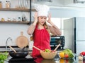 Asian stressed depressed worried female frowning face chef housewife wears white tall cook hat apron standing holding hands on Royalty Free Stock Photo