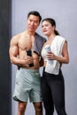 Asian strong fit young male muscular shirtless fitness model in sporty shorts and female athlete in sport bra standing smiling Royalty Free Stock Photo