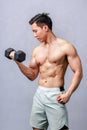 Asian strong handsome fit young male muscular shirtless fitness model athlete in sporty shorts standing posing lifting weight Royalty Free Stock Photo