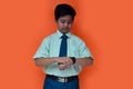 asian student boy looking watch, isolated ata orange background Royalty Free Stock Photo