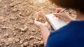 Asian student doing research or checking dry soil in empty land for planting