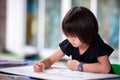 Asian student girl doing art on big paper. Child holding oil pastel color and fun coloring. Kid make craft at home. Royalty Free Stock Photo