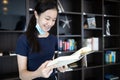 Asian student girl in a protective medical mask under her chin,wrong way to wear a face mask,child girl standing and reading a