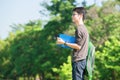 Asian student holding books and smiling while standing in park a Royalty Free Stock Photo