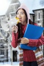 Asian student in winter clothes shouting with megaphone