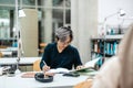 Asian student writing in notebook at table in library