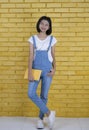 Asian student young girl hold book with yellow blocks wall in happy emotion Royalty Free Stock Photo