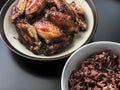 Asian style air fried chicken wings with ceramic dish serve with small bowl of cooked Rice berry. On black background. Royalty Free Stock Photo