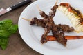 Asian style grilled teriyaki beef skewers on a white plate, top view. Delicious appetizer